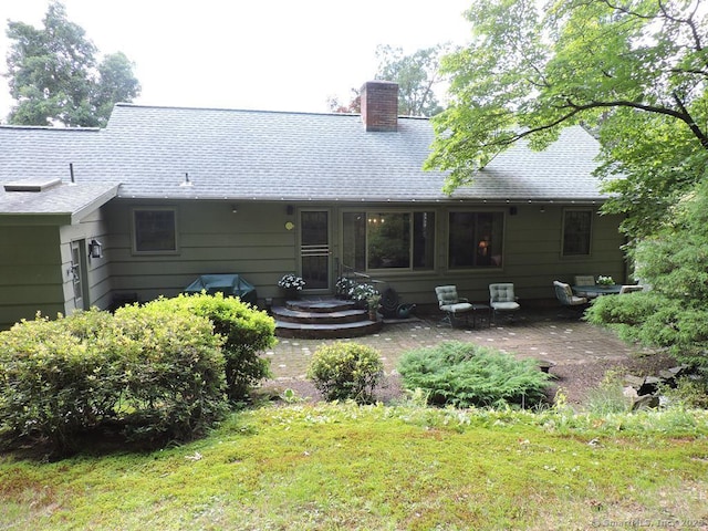 29 Graham Rd, East Windsor, CT 06016 - back of house featuring a chimney, a shingled roof, a patio, and a lawn