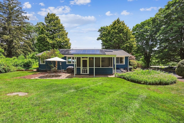 103 Glenwood Rd, Clinton, CT 06413 - back of property with a sunroom, roof mounted solar panels, a lawn, and a patio area