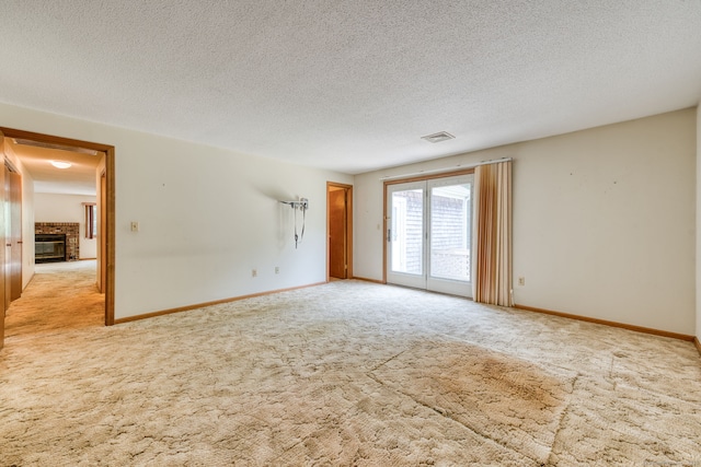 120 Songbird Ln Unit 120, Farmington, CT 06032 - spare room featuring light carpet, a brick fireplace, and a textured ceiling