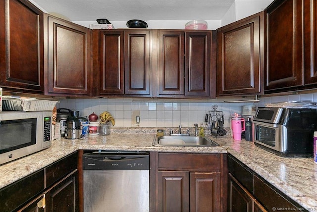 11 Bedford Ave Apt J2, Norwalk, CT 06850 - kitchen with stainless steel appliances, backsplash, dark brown cabinetry, and light stone counters