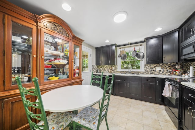 1 Oakridge Dr, Enfield, CT 06082 - kitchen with black range with electric stovetop, stainless steel microwave, tasteful backsplash, light countertops, and light tile patterned floors
