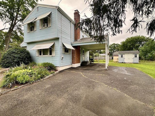 52 Midland Rd, Windsor Locks, CT 06096 - view of property exterior featuring asphalt driveway, a chimney, a carport, and a storage unit