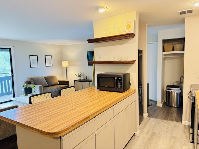 110 Trolley Crossing Ln Unit 110, Middletown, CT 06457 - kitchen with open shelves, black microwave, light wood-style flooring, white cabinetry, and open floor plan