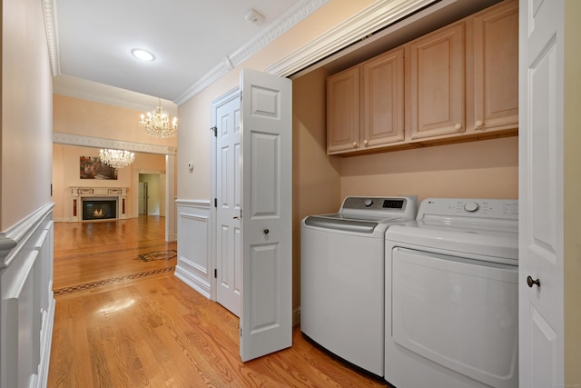 9 Old Logging Rd, Stamford, CT 06903 - laundry room with cabinet space, a chandelier, washing machine and dryer, ornamental molding, and light wood finished floors