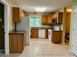 1929 Logans Way, Windsor, CT 06095 - kitchen featuring white appliances, brown cabinetry, light tile patterned flooring, and dark countertops