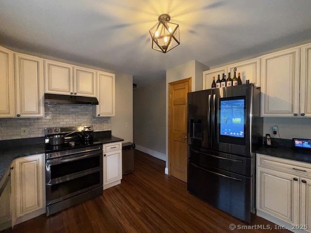 67 Bergendahl Dr, Griswold, CT 06351 - kitchen featuring stainless steel appliances, dark countertops, dark wood-style floors, tasteful backsplash, and under cabinet range hood