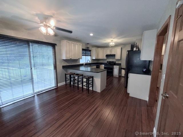 67 Bergendahl Dr, Griswold, CT 06351 - kitchen featuring a peninsula, dark countertops, a ceiling fan, a breakfast bar, and range with gas stovetop