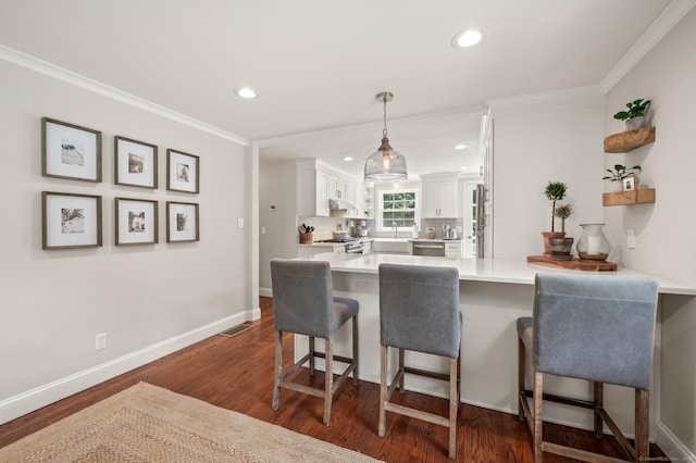 73 Water St, Glastonbury, CT 06073 - kitchen featuring a peninsula, white cabinets, dark wood-style floors, a kitchen breakfast bar, and light countertops