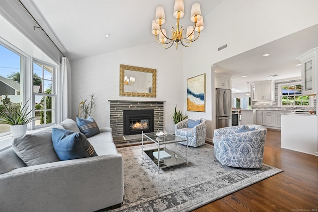 68 William St, Norwalk, CT 06851 - living room featuring dark wood-style flooring, healthy amount of natural light, a glass covered fireplace, a high ceiling, and a chandelier