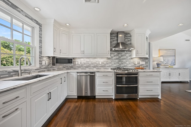 68 William St, Norwalk, CT 06851 - kitchen with appliances with stainless steel finishes, wall chimney exhaust hood, dark wood-type flooring, tasteful backsplash, and recessed lighting