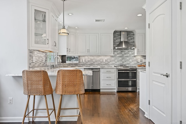 68 William St, Norwalk, CT 06851 - kitchen with stainless steel appliances, wall chimney exhaust hood, a peninsula, glass insert cabinets, and white cabinetry