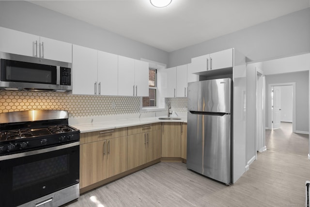 276 Bond St, Bridgeport, CT 06610 - kitchen featuring appliances with stainless steel finishes, light wood finished floors, tasteful backsplash, light stone countertops, and white cabinetry