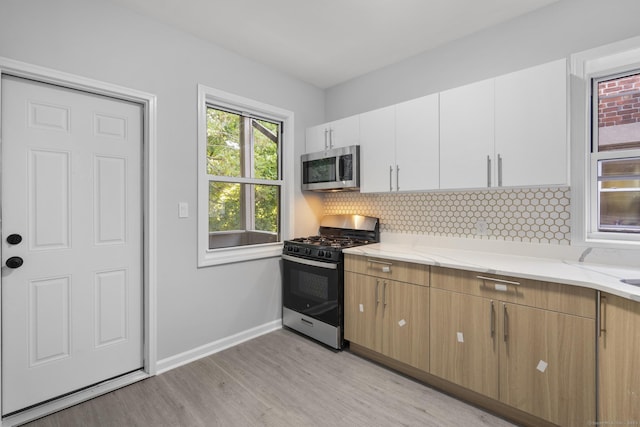 276 Bond St, Bridgeport, CT 06610 - kitchen featuring stainless steel appliances, light wood finished floors, decorative backsplash, white cabinetry, and light stone countertops