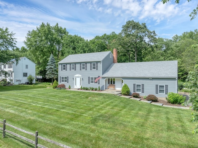 35 Pheasant Ln, Ridgefield, CT 06877 - colonial home with a front yard, a chimney, and view of scattered trees