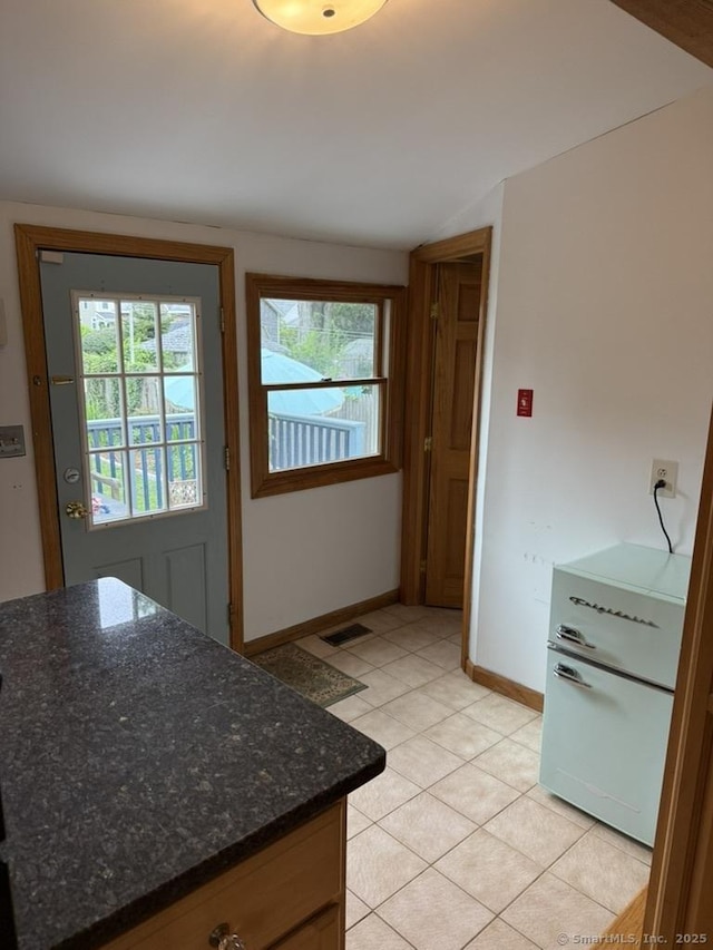 19 Hartford Ave, Old Saybrook, CT 06475 - kitchen with lofted ceiling, light tile patterned floors, dark stone counters, and white refrigerator