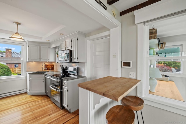8 Fenbrook Rd, Old Saybrook, CT 06475 - kitchen with stainless steel appliances, decorative backsplash, a tray ceiling, light wood-type flooring, and pendant lighting