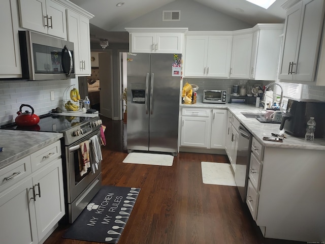 191 Dawson Ave, West Haven, CT 06516 - kitchen with appliances with stainless steel finishes, vaulted ceiling, decorative backsplash, and white cabinetry