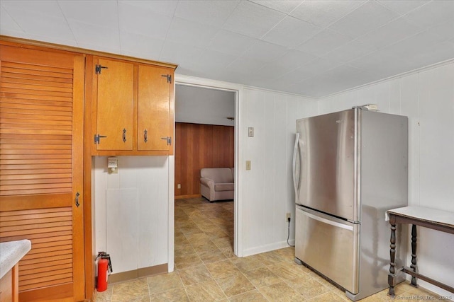 496 Mulberry St, Southington, CT 06479 - kitchen featuring freestanding refrigerator, wooden walls, and brown cabinets
