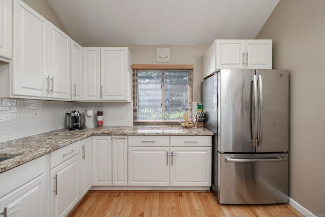 2289 Bedford St Unit F2, Stamford, CT 06905 - kitchen featuring freestanding refrigerator, light wood-style floors, vaulted ceiling, backsplash, and white cabinetry