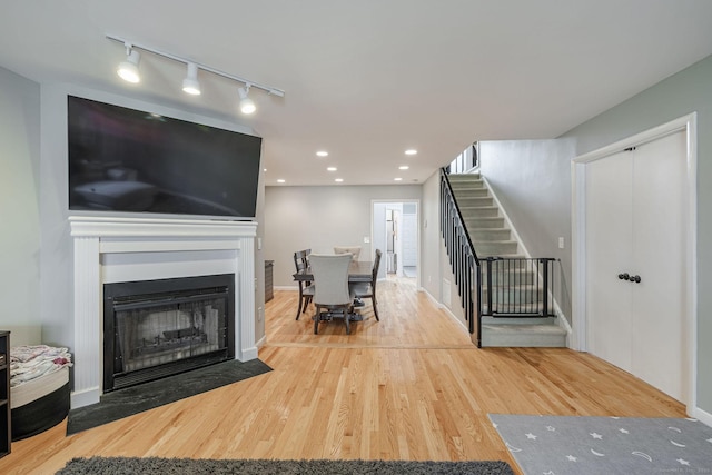 2289 Bedford St Unit F2, Stamford, CT 06905 - living room featuring rail lighting, stairs, wood finished floors, and a fireplace with flush hearth