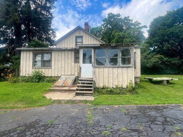 130 Wilkins Ave, Bridgeport, CT 06606 - view of front of house with a chimney, a front lawn, board and batten siding, and entry steps