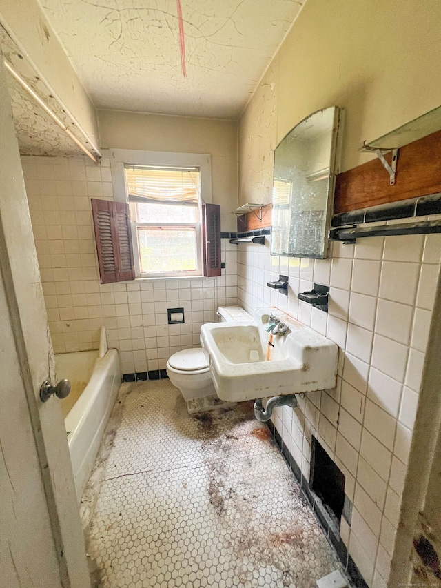 130 Wilkins Ave, Bridgeport, CT 06606 - bathroom featuring tile walls, a bath, a textured ceiling, and wainscoting