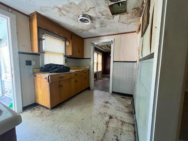 130 Wilkins Ave, Bridgeport, CT 06606 - kitchen featuring tile walls, a wainscoted wall, brown cabinetry, light countertops, and crown molding