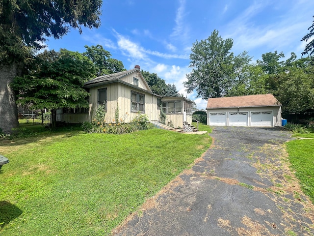 130 Wilkins Ave, Bridgeport, CT 06606 - view of front of house with board and batten siding, an outbuilding, a detached garage, a chimney, and a front lawn