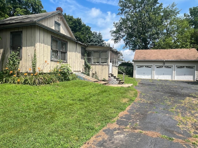 130 Wilkins Ave, Bridgeport, CT 06606 - view of side of home with an outdoor structure, board and batten siding, a detached garage, and a yard