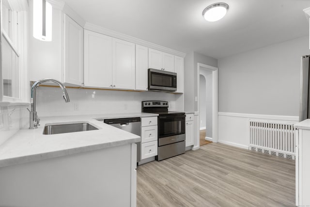 106 Lakeview Ave, West Haven, CT 06516 - kitchen with stainless steel appliances, radiator heating unit, white cabinetry, light wood-style flooring, and backsplash
