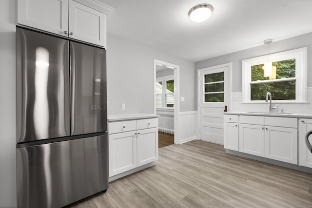 106 Lakeview Ave, West Haven, CT 06516 - kitchen featuring freestanding refrigerator, light countertops, light wood-style flooring, healthy amount of natural light, and a wainscoted wall