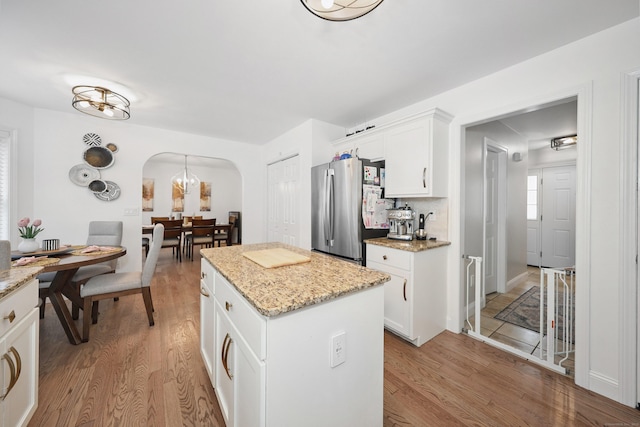 357 D Welton Way, Thomaston, CT 06787 - kitchen with arched walkways, freestanding refrigerator, light wood finished floors, and a kitchen island