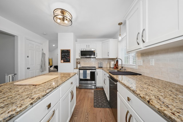 357 D Welton Way, Thomaston, CT 06787 - kitchen featuring appliances with stainless steel finishes, wood finished floors, white cabinets, light stone countertops, and tasteful backsplash