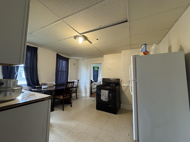 150 Greenwood St, New Britain, CT 06051 - kitchen with freestanding refrigerator, a paneled ceiling, black gas range oven, and light floors