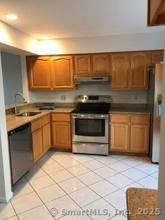 55 Mill Plain Rd Unit 17-6, Danbury, CT 06811 - kitchen featuring appliances with stainless steel finishes, light tile patterned flooring, under cabinet range hood, and brown cabinets
