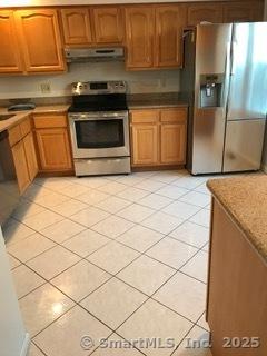 55 Mill Plain Rd Unit 17-6, Danbury, CT 06811 - kitchen with appliances with stainless steel finishes, light tile patterned flooring, under cabinet range hood, and brown cabinets