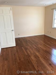 55 Mill Plain Rd Unit 17-6, Danbury, CT 06811 - empty room featuring dark wood-style flooring and baseboards