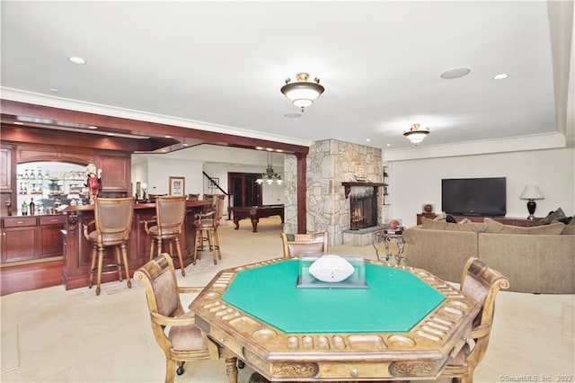 game room featuring light carpet, bar area, a notable chandelier, a fireplace, and ornamental molding