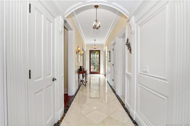 hall with crown molding, a notable chandelier, and light tile floors