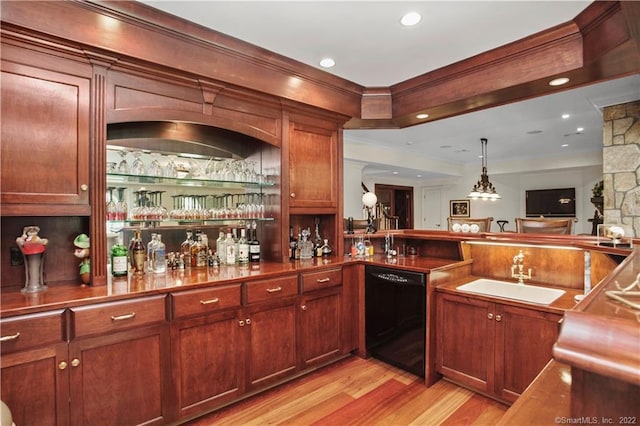 bar featuring light hardwood / wood-style floors, pendant lighting, black dishwasher, and sink