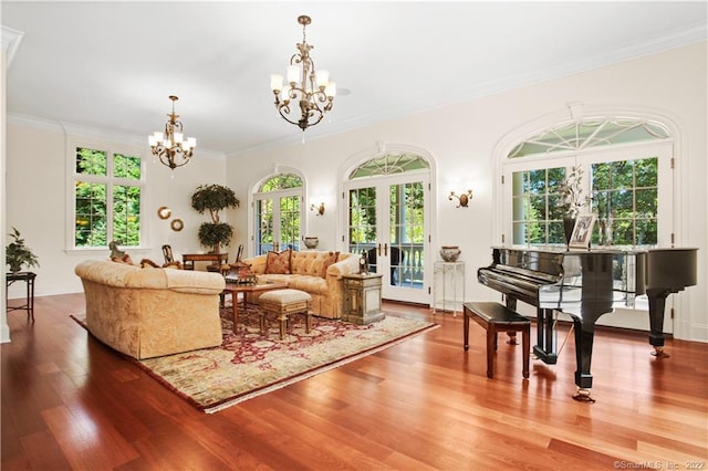 living room featuring a chandelier, ornamental molding, light hardwood / wood-style flooring, and french doors