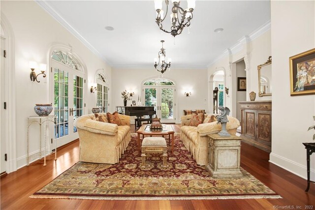 living room with crown molding, french doors, an inviting chandelier, and dark hardwood / wood-style flooring