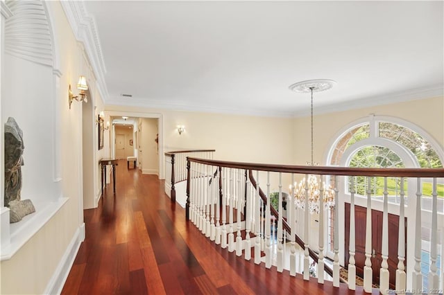 hall featuring an inviting chandelier, crown molding, and dark wood-type flooring