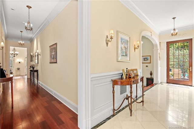 tiled foyer entrance featuring crown molding and a notable chandelier