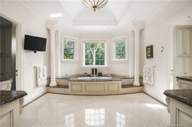 bathroom featuring tile flooring, a tray ceiling, ornamental molding, decorative columns, and a tub