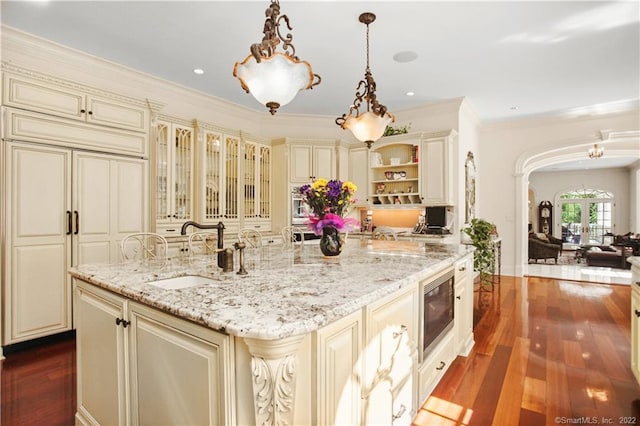 kitchen with cream cabinets, dark wood-type flooring, sink, and pendant lighting