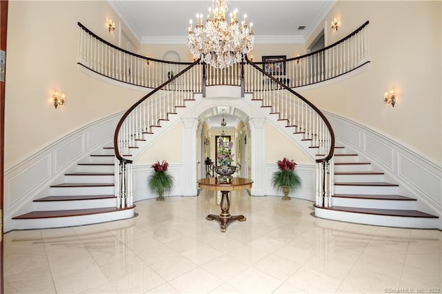 stairs featuring light tile floors, a chandelier, crown molding, and a towering ceiling