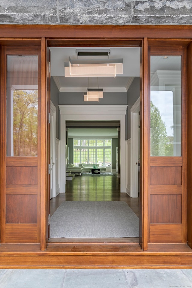 corridor with ornamental molding and wood finished floors