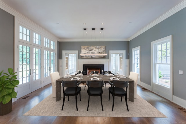 dining space featuring crown molding, a glass covered fireplace, and wood finished floors