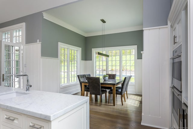 dining area with a wainscoted wall, ornamental molding, and dark wood-style floors